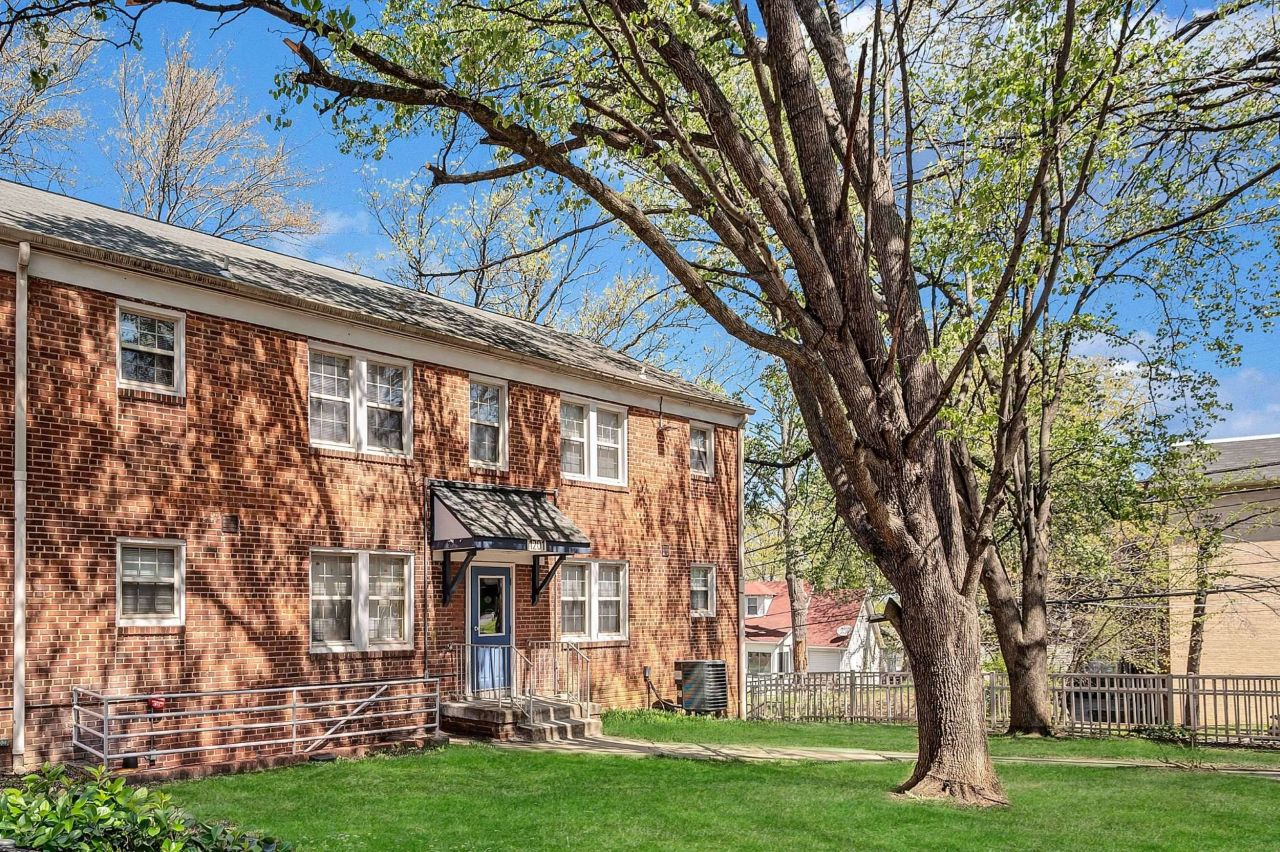 Exterior image of brick apartment building and large tree
